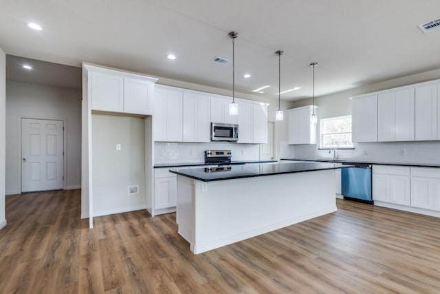 kitchen with pendant lighting, white cabinetry, stainless steel appliances, dark hardwood / wood-style floors, and a center island