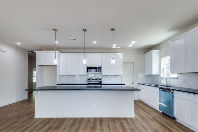 kitchen with white cabinetry, appliances with stainless steel finishes, a center island, and pendant lighting