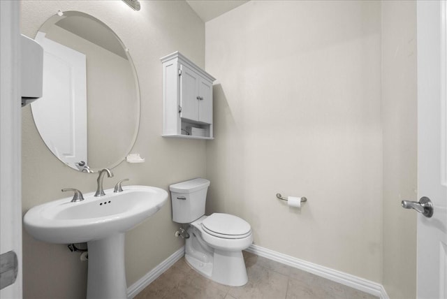 bathroom featuring toilet, tile patterned flooring, and baseboards