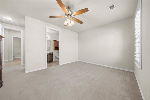 unfurnished bedroom with baseboards, connected bathroom, visible vents, and light colored carpet