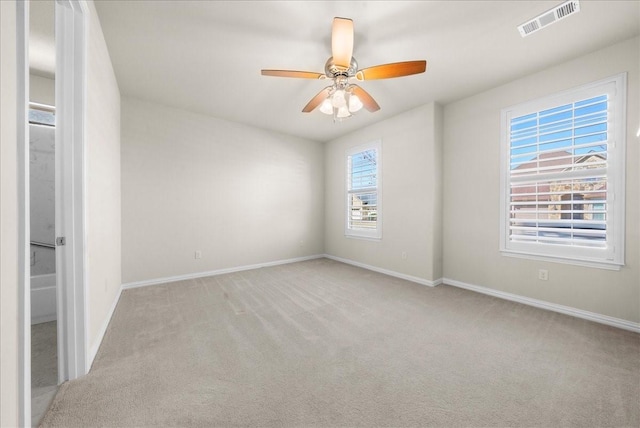 spare room with ceiling fan, carpet, visible vents, and baseboards