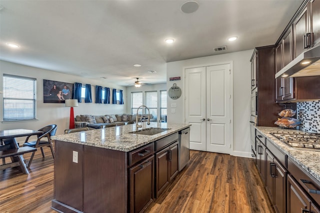 kitchen with light stone countertops, an island with sink, appliances with stainless steel finishes, and sink