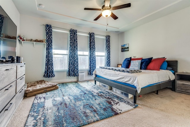 carpeted bedroom featuring a tray ceiling and ceiling fan