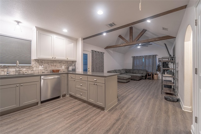 kitchen with sink, lofted ceiling with beams, light wood-type flooring, stainless steel dishwasher, and kitchen peninsula