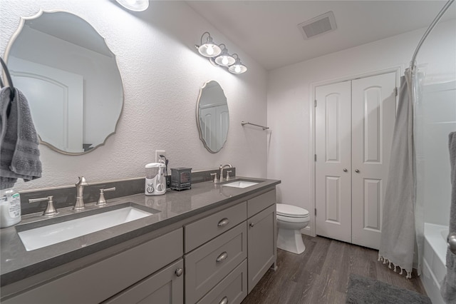 full bathroom with vanity, hardwood / wood-style floors, shower / tub combo, and toilet