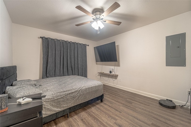 bedroom with ceiling fan, dark wood-type flooring, electric panel, and a textured ceiling