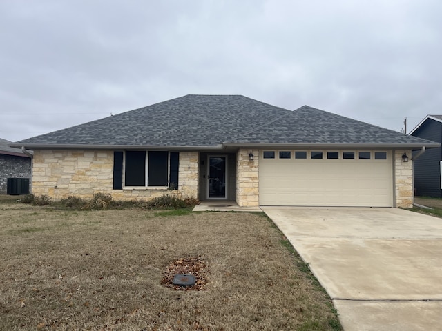 view of front facade featuring a garage, a front yard, and central air condition unit