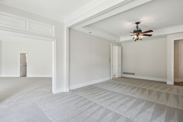 carpeted empty room with ceiling fan, ornamental molding, and a raised ceiling