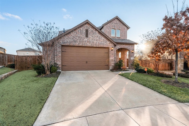 view of front facade featuring a front yard, concrete driveway, brick siding, and fence