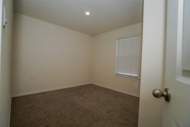 unfurnished room with dark colored carpet