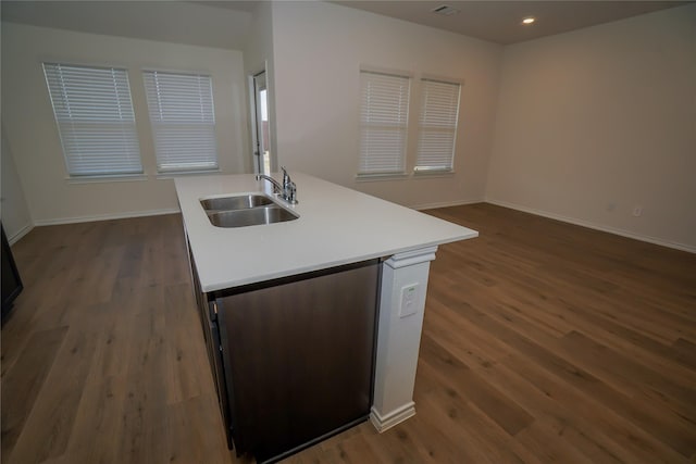 kitchen with sink, an island with sink, dark hardwood / wood-style flooring, and dishwashing machine