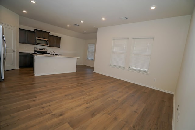 kitchen featuring a center island with sink, dark brown cabinets, stainless steel appliances, dark hardwood / wood-style flooring, and sink