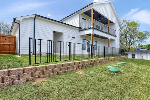 back of property featuring ceiling fan, a yard, and a balcony