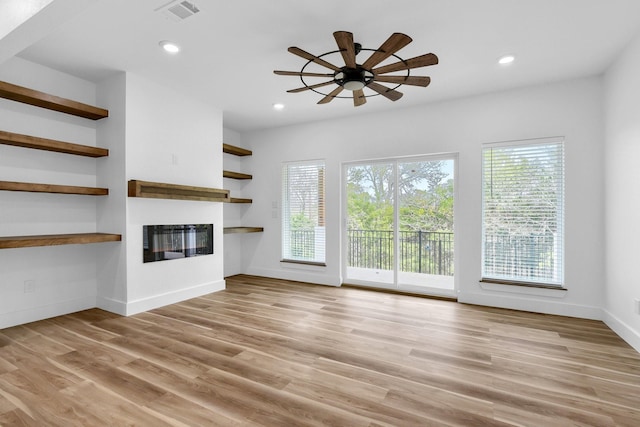 unfurnished living room with a wealth of natural light, light hardwood / wood-style floors, and ceiling fan