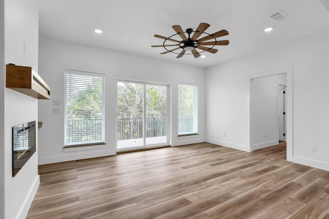 unfurnished living room featuring ceiling fan, plenty of natural light, and light hardwood / wood-style floors