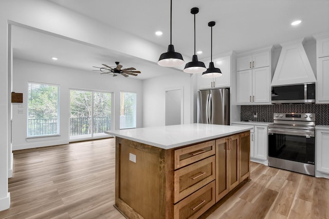 kitchen featuring white cabinetry, a center island, wall chimney exhaust hood, and appliances with stainless steel finishes