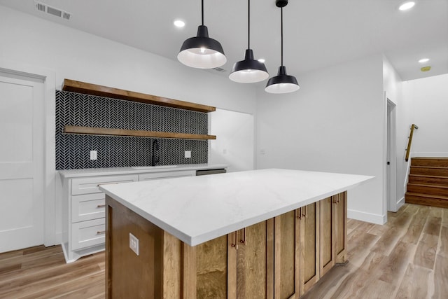 kitchen with pendant lighting, light wood-type flooring, white cabinets, and a kitchen island