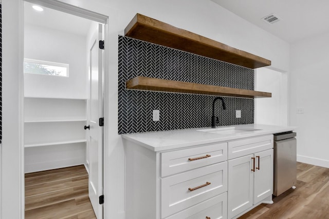 interior space featuring sink, white cabinetry, backsplash, stainless steel dishwasher, and light wood-type flooring