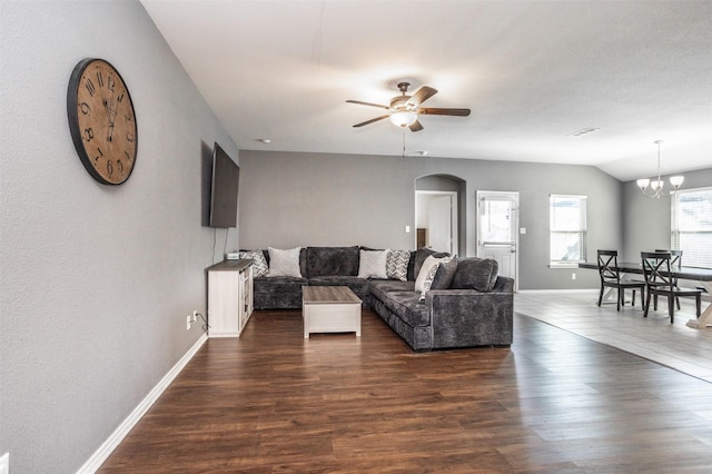 living room with vaulted ceiling, dark wood-type flooring, and ceiling fan with notable chandelier