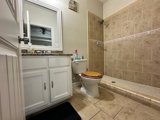 bathroom featuring tiled shower, vanity, toilet, and tile patterned flooring