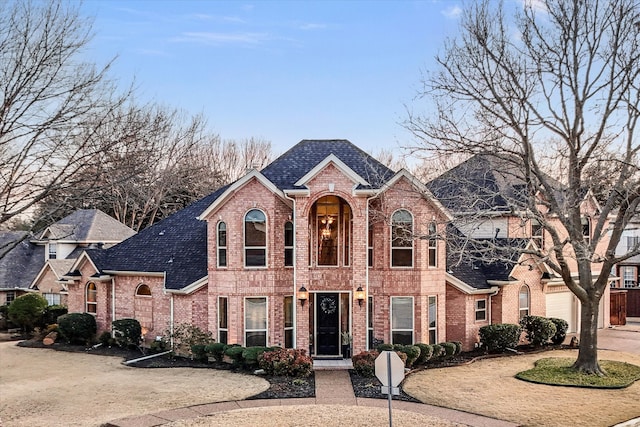 view of front of home featuring driveway, brick siding, and roof with shingles