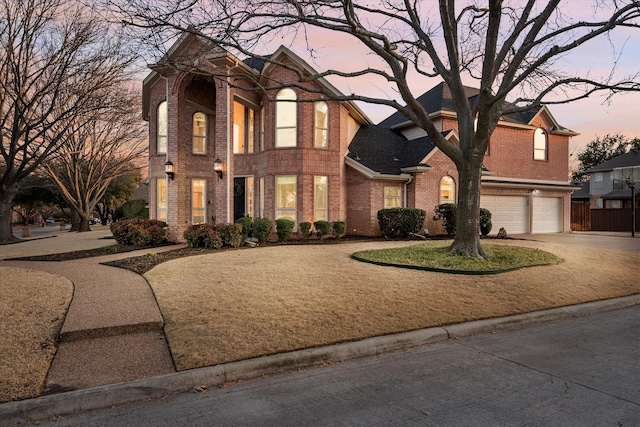 view of front of property featuring a garage, concrete driveway, brick siding, and fence