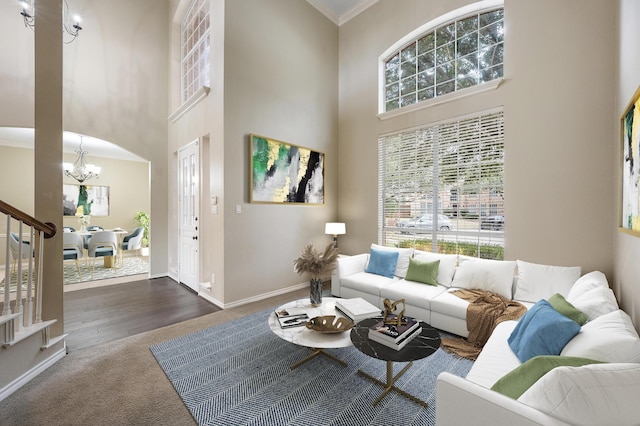 carpeted living room featuring a high ceiling, ornamental molding, and an inviting chandelier