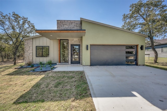 view of front of house featuring stucco siding, concrete driveway, an attached garage, board and batten siding, and a front lawn