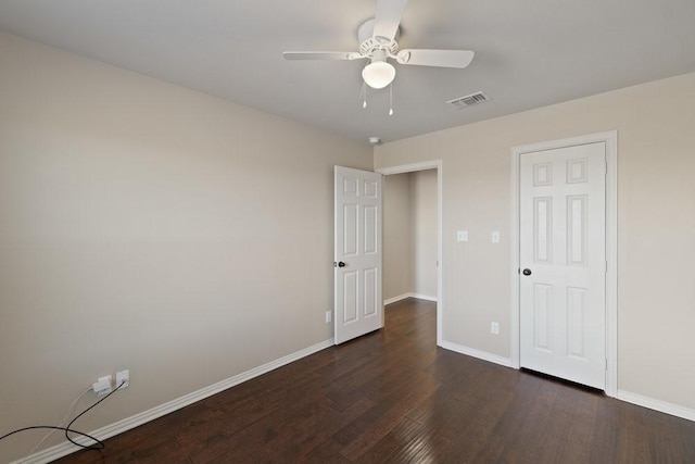empty room with visible vents, dark wood-style flooring, baseboards, and ceiling fan