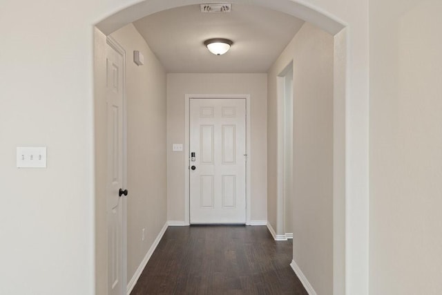 doorway to outside featuring baseboards, dark wood-style floors, visible vents, and arched walkways