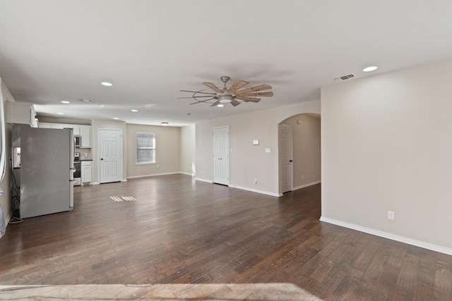 unfurnished living room with a ceiling fan, baseboards, dark wood-style flooring, arched walkways, and recessed lighting