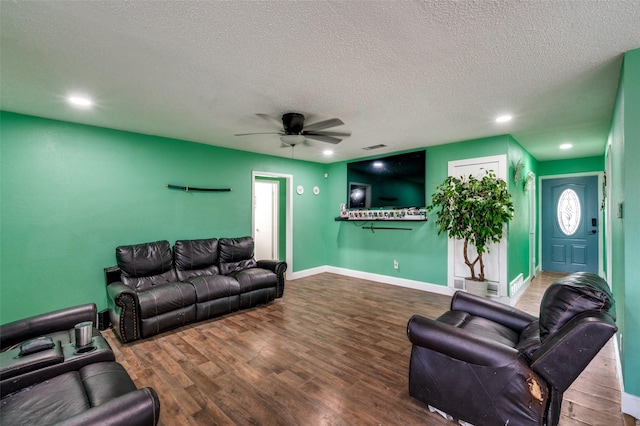 living room featuring a textured ceiling, wood-type flooring, and ceiling fan