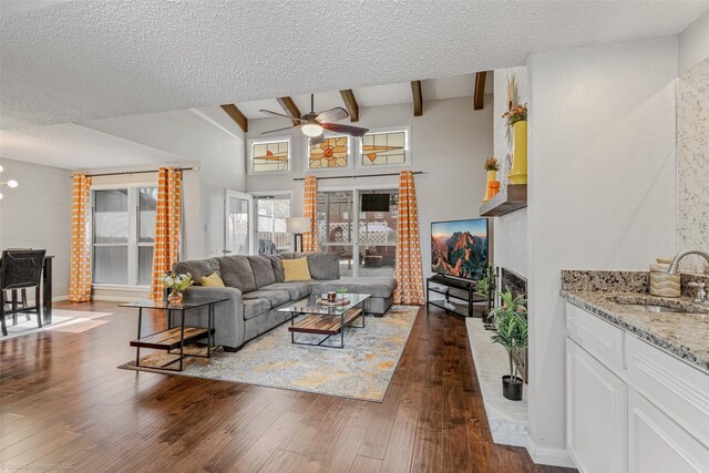 dining area featuring a textured ceiling, ceiling fan with notable chandelier, lofted ceiling with beams, a brick fireplace, and dark wood-type flooring