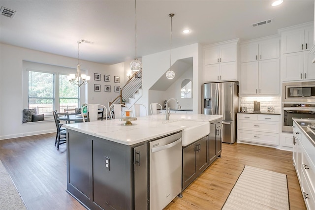 517 Ramon St, Burleson, TX 76028 - kitchen with appliances with stainless steel finishes, a chandelier, white cabinets, light stone counters, and a kitchen island with sink