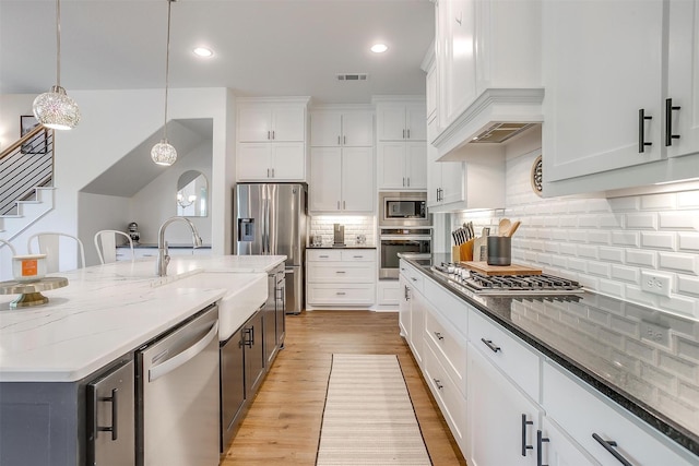 517 Ramon St, Burleson, TX 76028 - kitchen featuring stainless steel appliances, custom exhaust hood, white cabinetry, light stone countertops, and hanging light fixtures
