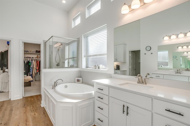 517 Ramon St, Burleson, TX 76028 - bathroom featuring a high ceiling, a stall shower, a walk in closet, a garden tub, and wood finished floors
