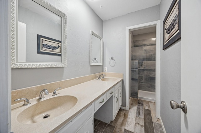 7316 Martha Ln, Fort Worth, TX 76112 - bathroom featuring wood finished floors, double vanity, a tile shower, and baseboards