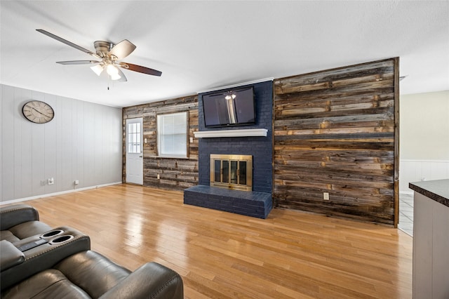 living room with a fireplace, ceiling fan, and wood-type flooring