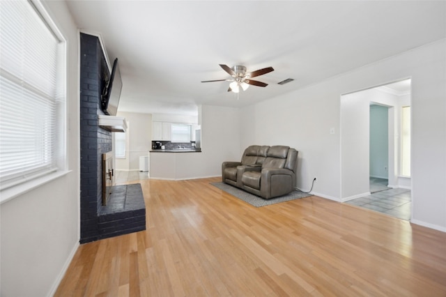 7316 Martha Ln, Fort Worth, TX 76112 - unfurnished room featuring ceiling fan, light wood-style flooring, a brick fireplace, and baseboards