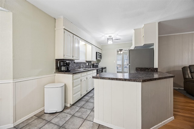 7316 Martha Ln, Fort Worth, TX 76112 - kitchen featuring stainless steel appliances, ceiling fan, dark countertops, a sink, and white cabinetry
