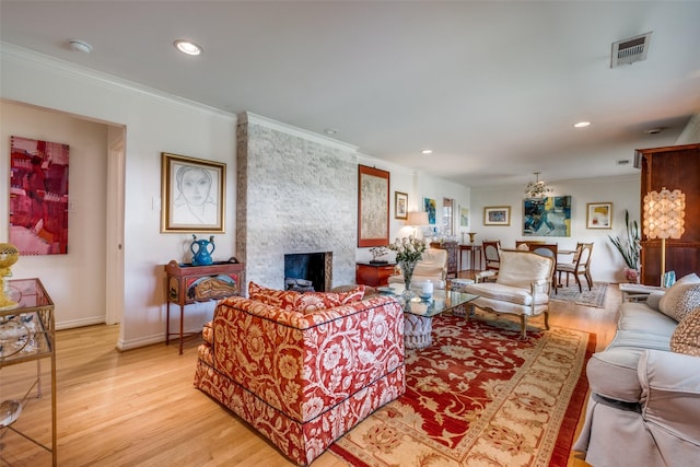 living room with a fireplace, crown molding, and light hardwood / wood-style flooring