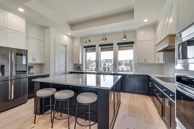 2770 Fireside Dr, Midlothian, TX 76065 - kitchen with appliances with stainless steel finishes, light wood-style flooring, decorative backsplash, a center island, and a breakfast bar area