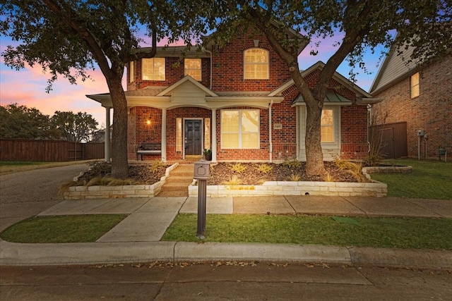 view of front of home featuring fence, a porch, and brick siding