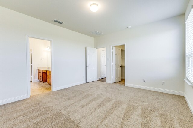 3917 Belleview Pl, Crandall, TX 75114 - unfurnished bedroom featuring visible vents, a walk in closet, ensuite bath, baseboards, and light colored carpet