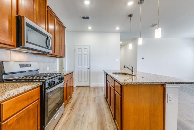 3917 Belleview Pl, Crandall, TX 75114 - kitchen with light stone counters, a sink, light wood-style flooring, appliances with stainless steel finishes, and visible vents