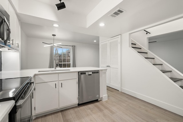 kitchen with white cabinetry, kitchen peninsula, appliances with stainless steel finishes, and light wood-type flooring