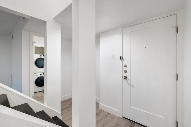 entryway featuring stacked washer / drying machine and light hardwood / wood-style floors