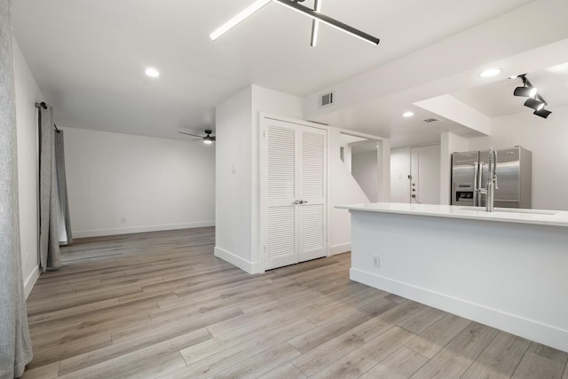 kitchen with light hardwood / wood-style floors, ceiling fan, stainless steel fridge, and kitchen peninsula