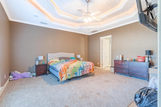 carpeted bedroom with ceiling fan, a tray ceiling, and ornamental molding