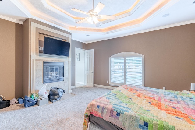 bedroom with a fireplace, ornamental molding, light colored carpet, and a raised ceiling